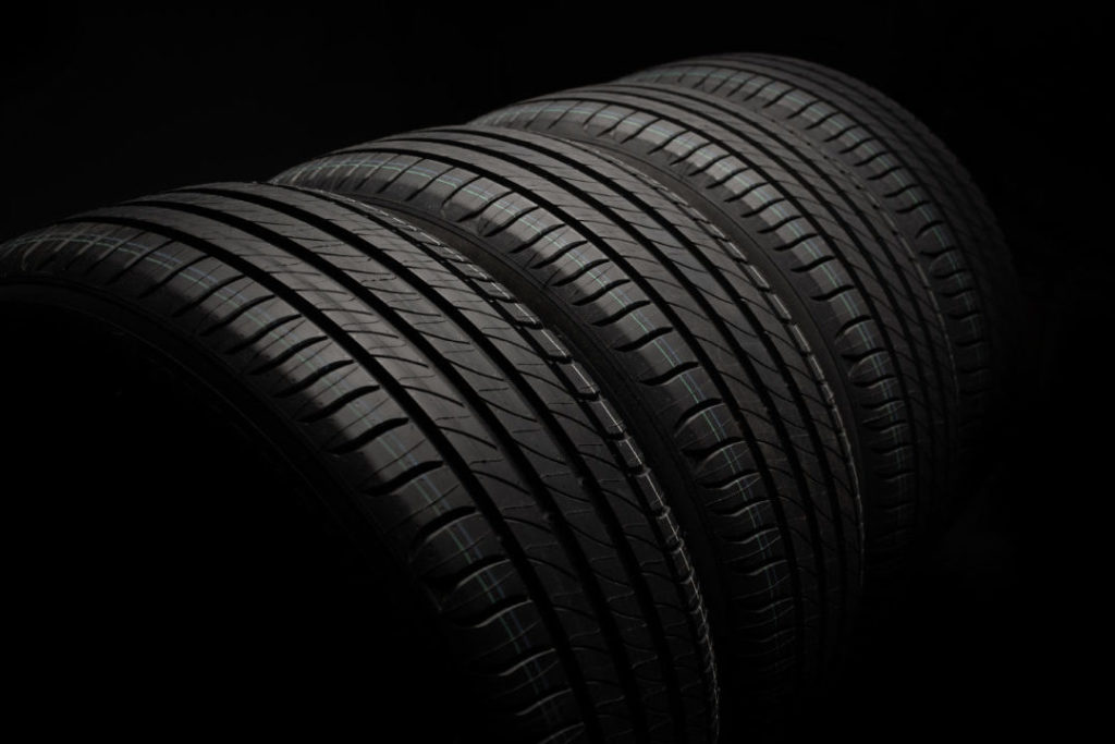 new-car-tires-group-road-wheels-dark-background-summer-tires-with-asymmetric-tread-design-driving-car-concept-e1652336778860